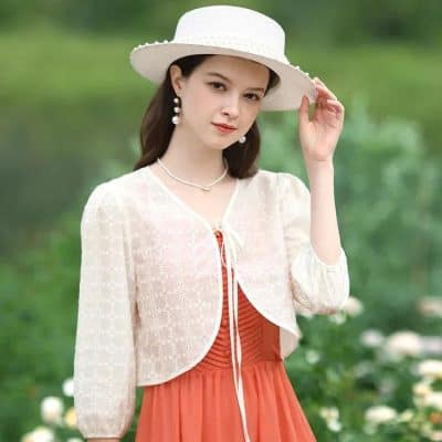 A stylish woman in a wide-brim hat with elegant earrings and a lace cover-up showcasing fashionable optical accessories in a scenic outdoor setting.