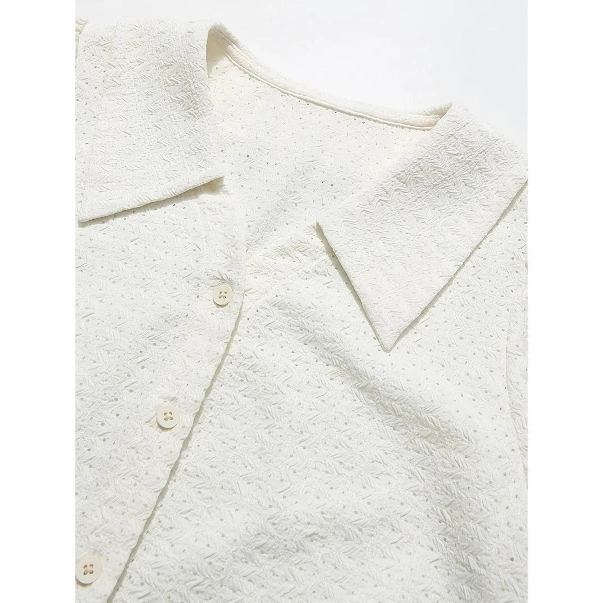 Elegant white textured blouse with delicate details for women.