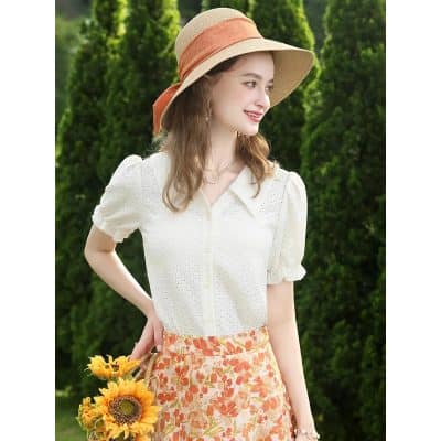 Young woman wearing sun hat and floral skirt, enjoying outdoors in vibrant garden, perfect for summer fashion, relaxation, and outdoor lifestyle.