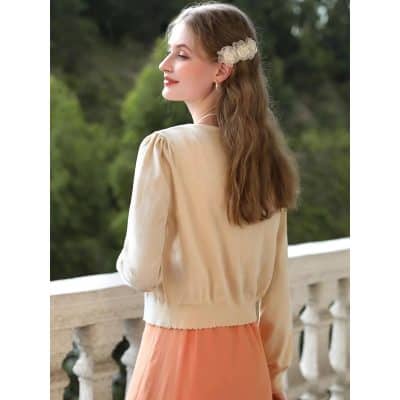 A stylish woman wearing a beige optician cardigan with puffed sleeves, perfect for a fashionable and comfortable look. Ideal for casual outings or outdoor events, highlighting quality and elegant design in women's fashion.