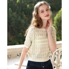 Beautiful young woman outdoors wearing stylish sweater, natural glow, serene expression.