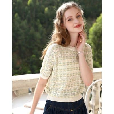 Beautiful young woman outdoors wearing stylish sweater, natural glow, serene expression.