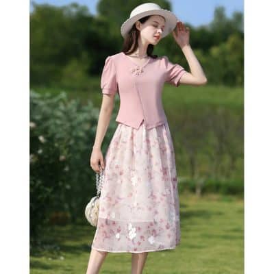 Beautiful woman wearing a pink floral midi dress, summer hat, and stylish handbag outdoors, showcasing fashionable women's clothing for spring and summer 2023.