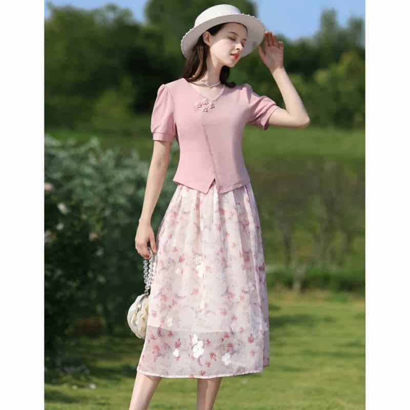 Beautiful woman wearing a pink floral midi dress, summer hat, and stylish handbag outdoors, showcasing fashionable women's clothing for spring and summer 2023.