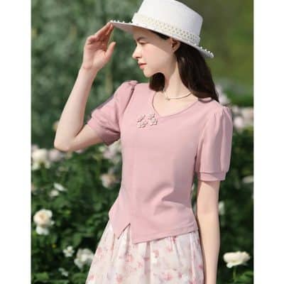 A stylish woman wearing a pink top and floral skirt, accessorized with a white hat, showcasing trendy summer outfit ideas perfect for outdoor visits and garden parties, emphasizing comfort and elegance.