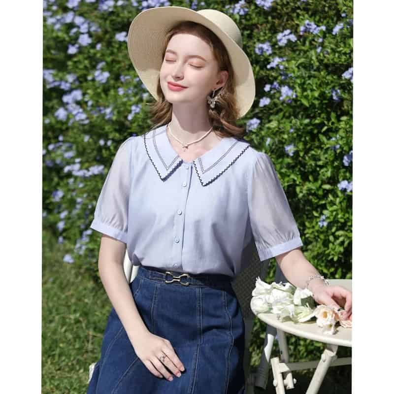 A stylish, light blue summer blouse with a decorative collar, perfect for outdoor wear and sun protection.