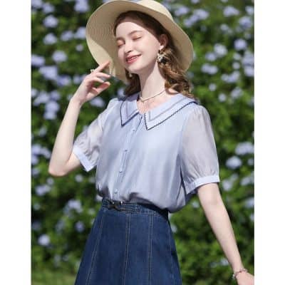 A young woman enjoying sunny weather with a stylish straw hat, light blue blouse, and denim skirt, perfect for summer outings. Experience casual chic and comfortable fashion for warm days.