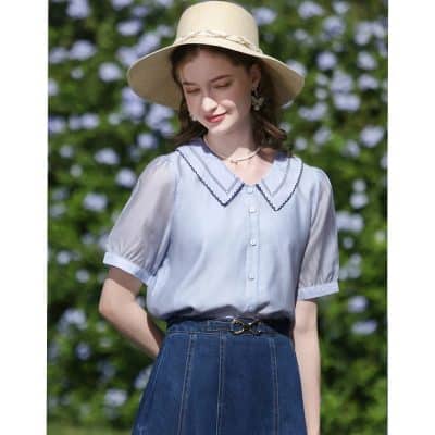 Chic women's blouse with embroidered contrasting detailing around the collar, short puff sleeves, and button-up front, ideal for stylish casual outfits or outdoor occasions. Available at Monalisa Medical.