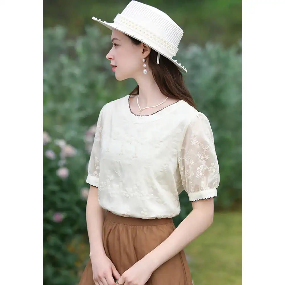 Soft white embroidered women's blouse with puff sleeves and delicate floral embroidery, perfect for stylish summer wear and outdoor occasions.