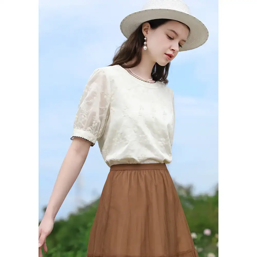 Stylish women's fashion blouse with delicate embroidery and short puff sleeves, perfect for summer or casual outings.