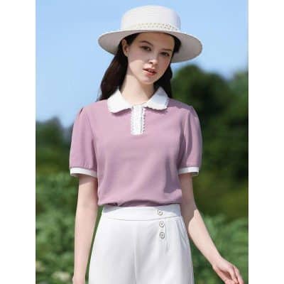 Beautiful young woman wearing pastel pink blouse with white collar and buttons, white high-waisted skirt, and sun hat enjoying outdoor sunny day.