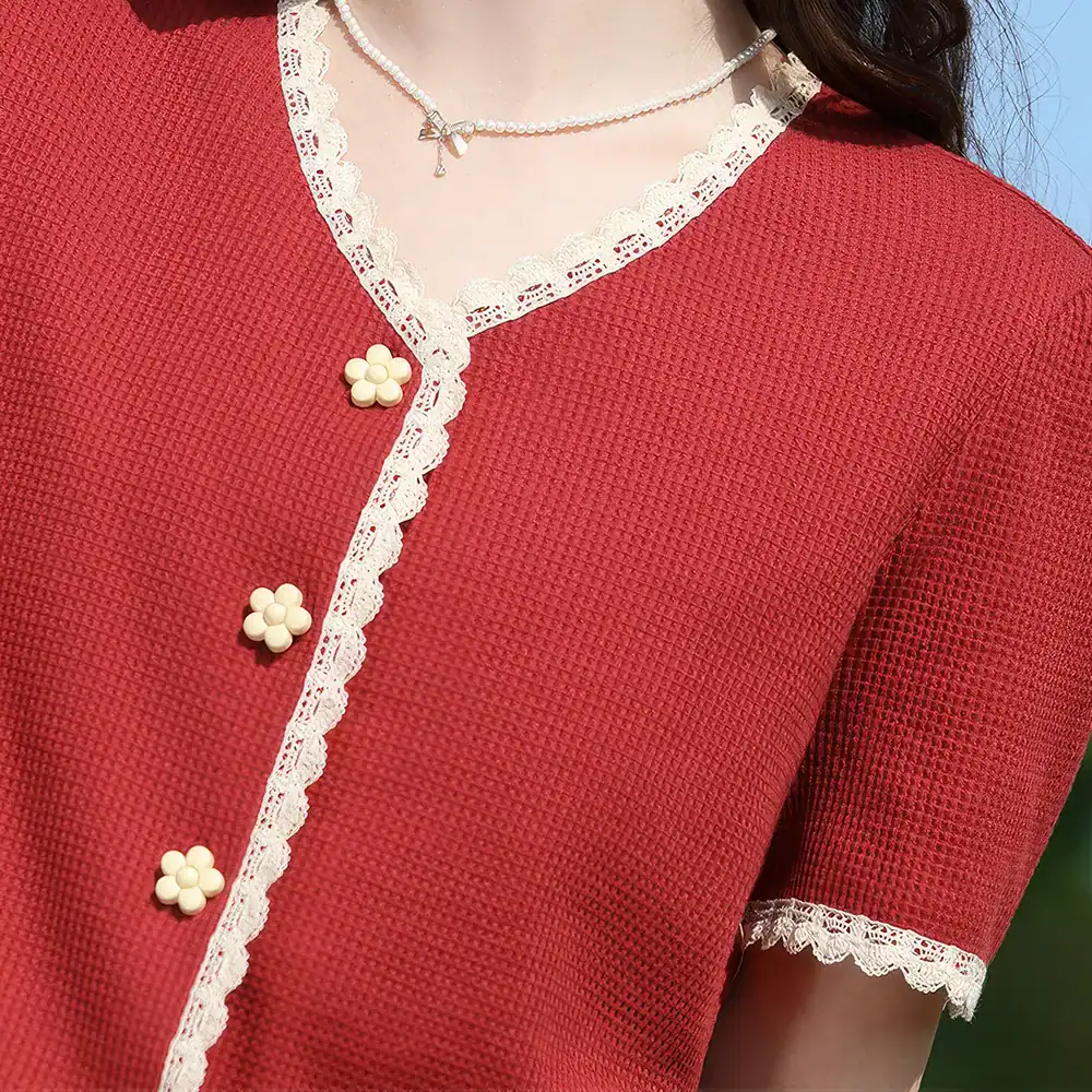 Close-up of a stylish red dress featuring lace accents, floral buttons, and a lace-trimmed neckline, perfect for fashion-forward women seeking sophisticated options.