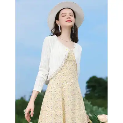 A stylish woman in a summer dress with a white blazer and accessories, enjoying sunny weather outdoors. Perfect for summer fashion, accessories, and outdoor style inspiration.