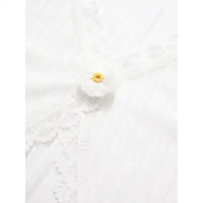 White lace fabric with intricate detailing and a small decorative flower accent, perfect for stylish occasions.