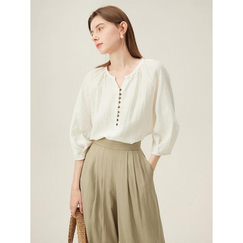 Stylish cream-colored blouse with button accents, ideal for office or casual outings, made from comfortable, lightweight fabric.