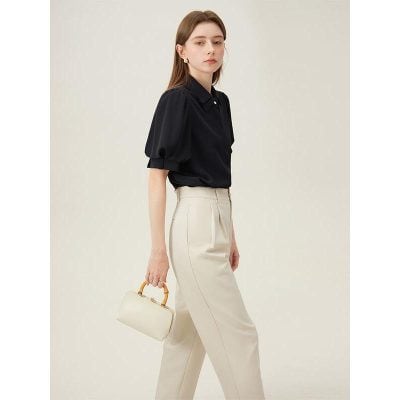 Elegant woman wearing professional black blouse and beige trousers with a stylish handbag, showcasing fashionable and comfortable office attire ideal for women.