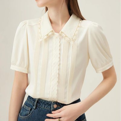 Stylish cream women's blouse featuring delicate lace collar, vertical pleats, and short puff sleeves, perfect for sophisticated fashion and office wear.