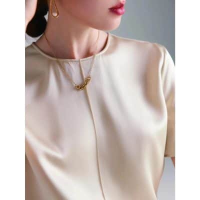 Light-colored blouse with a gold chain necklace, highlighting trendy fashion jewelry options available at Monalisa Store.