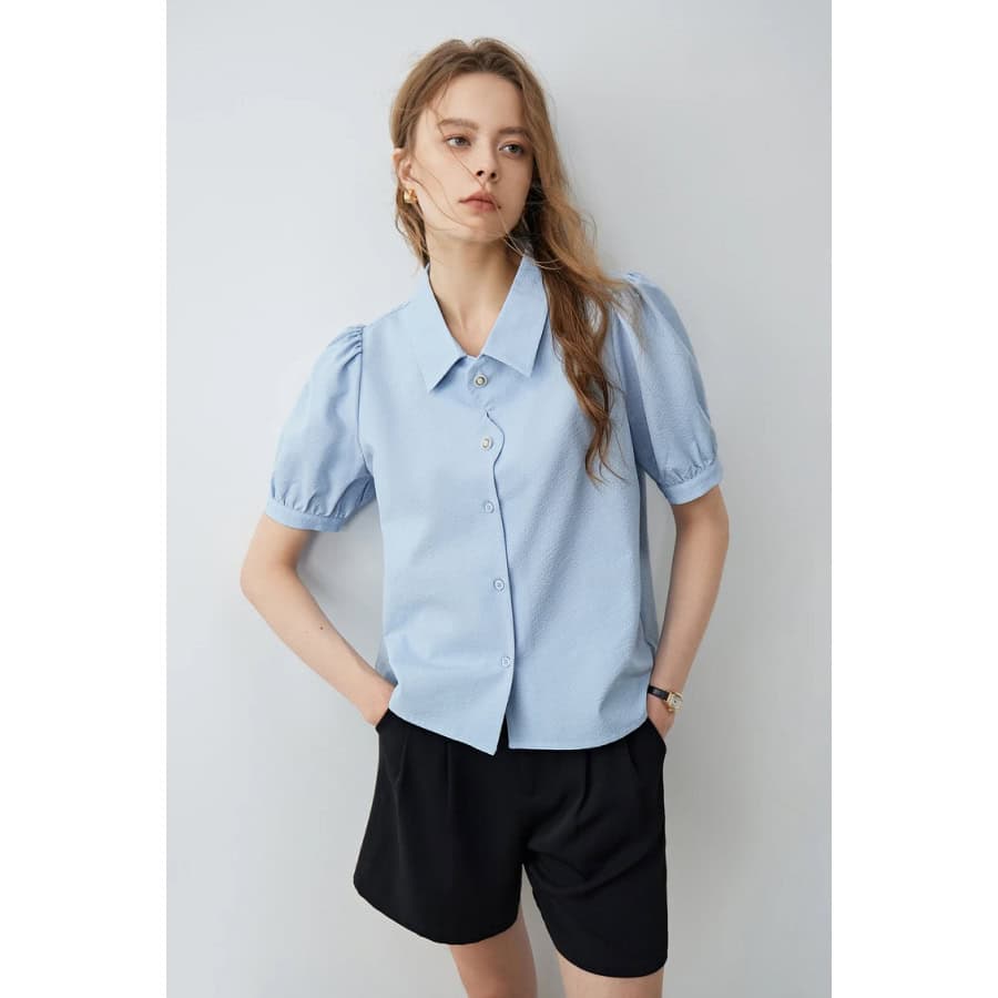 Elegant women's light blue button-up blouse with puff sleeves, perfect for office or casual wear. Durable, comfortable fabric ideal for modern fashion styles.