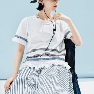 Girl wearing casual summer clothing with striped skirt and top, listening to music with headphones, showcasing relaxed fashion style ideal for vacations or casual outings.