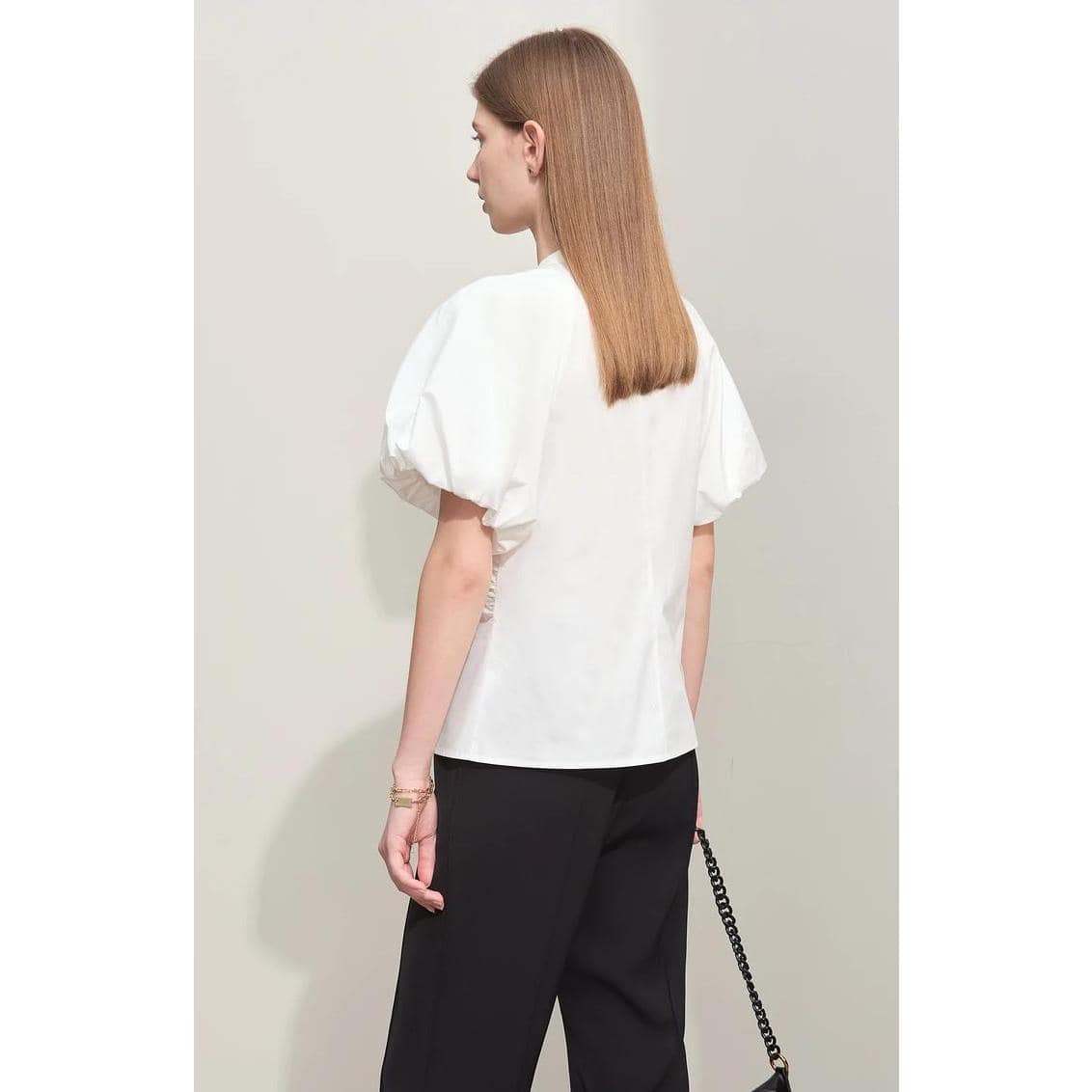 A stylish white blouse with voluminous puff sleeves, perfect for casual or office wear. Made from high-quality fabric, this top offers a chic and comfortable fit for women seeking fashionable apparel.