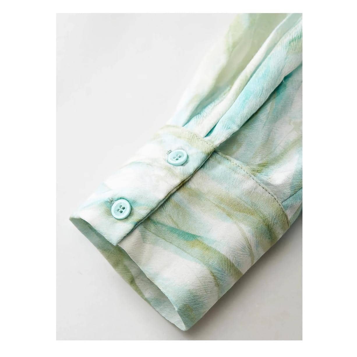 Soft pastel blouse with floral design and functional buttons, ideal for healthcare wear or medical office staff, combining fashion with professional comfort.