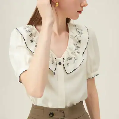 Vintage-inspired women's blouse with floral embroidery, scalloped edges, and comfortable fit, perfect for casual or dressy occasions.