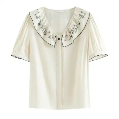 Antique white women’s blouse with floral embroidery, ruffled collar, and scalloped trim, perfect for sophisticated fashion.