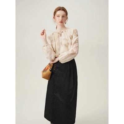 Stylish woman wearing a chic blouse and long black skirt, accessorized with earrings and a vintage bag, showcasing fashionable eyewear options available at Monalisa Store.