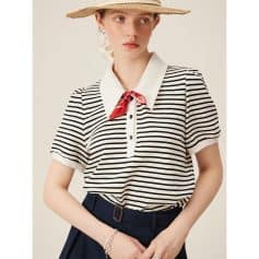Stylish woman wearing a navy and white striped polo shirt with a red silk necktie, paired with navy trousers and accessorized with bracelets, showcasing a trendy casual look.