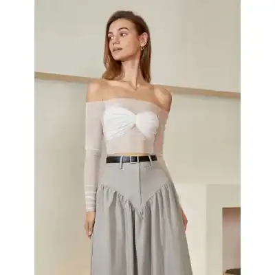 Elegant women's off-shoulder top with sheer long sleeves and ruching, styled with high-waisted beige wide-leg trousers, ideal for contemporary fashion and chic ensembles.