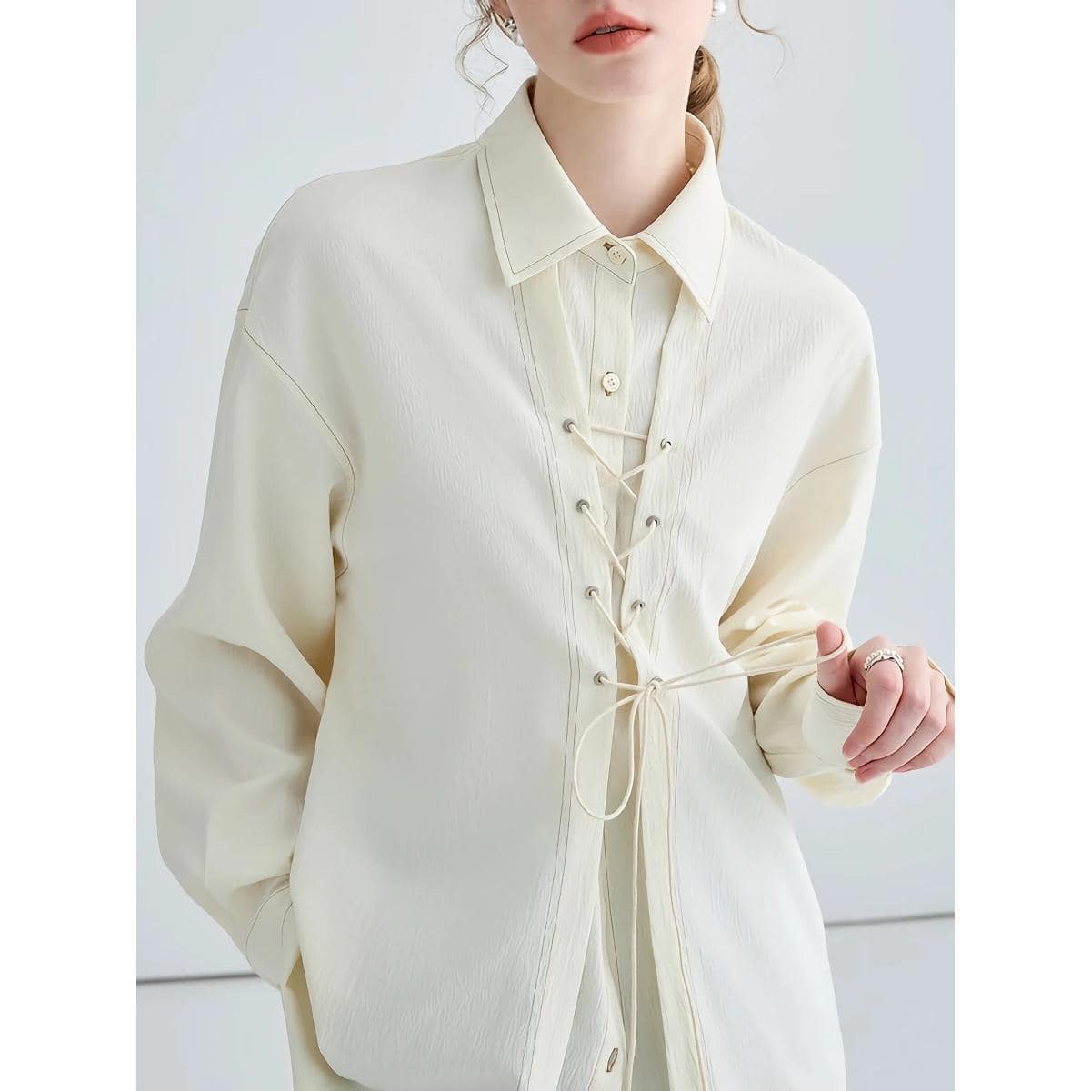 Light-colored women's fashion shirt with lace-up detail at the front, classic collar, and long sleeves. Perfect for stylish, modern looks, blending comfort and trendy design.