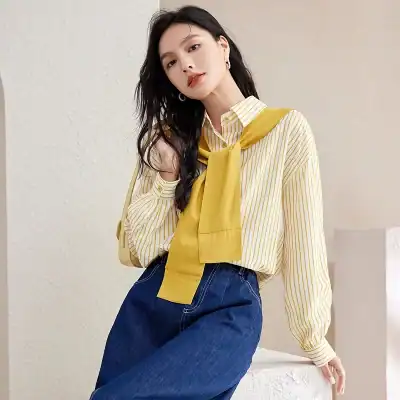 A fashionable yellow striped blouse with a matching sweater tied around the shoulders, perfect for a chic casual look.