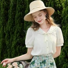 Beautiful woman wearing a cream-colored vintage blouse, floral skirt, and wide-brimmed hat, enjoying a sunny day outdoors. Perfect for spring and summer fashion, casual outings, and garden parties.