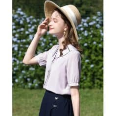 Elegant woman wearing sun hat and stylish sunglasses in outdoor setting with lush greenery background.