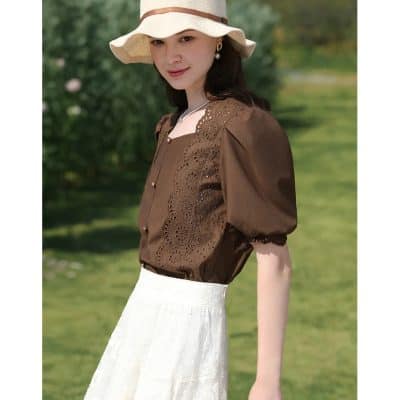 ALT text: Woman wearing fashionable brown eye care blouse with embroidery and a wide-brim hat outdoors, representing stylish eye health accessories from Monalisa Store.