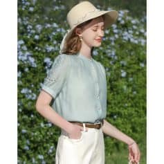 Beautiful young woman outdoors wearing light blue blouse and white pants with a sun hat, showcasing stylish summer clothing and accessories for women.