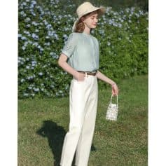 Beautiful woman in stylish spring outfit with hat and handbag outdoors.