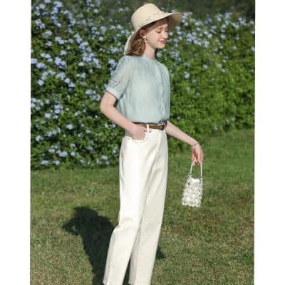 Beautiful woman in stylish spring outfit with hat and handbag outdoors.