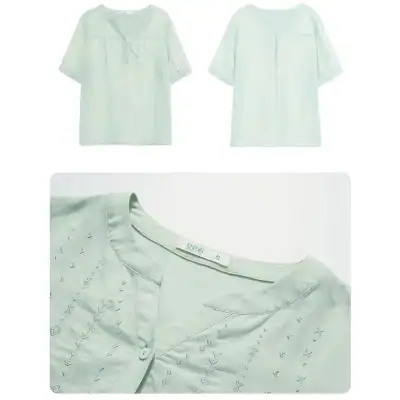 Close-up of a white, embroidered cotton blouse with subtle patterns and a round neckline, perfect for fashionable women's wear.