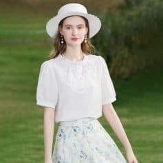 Young woman wearing stylish white hat and dress outdoors.