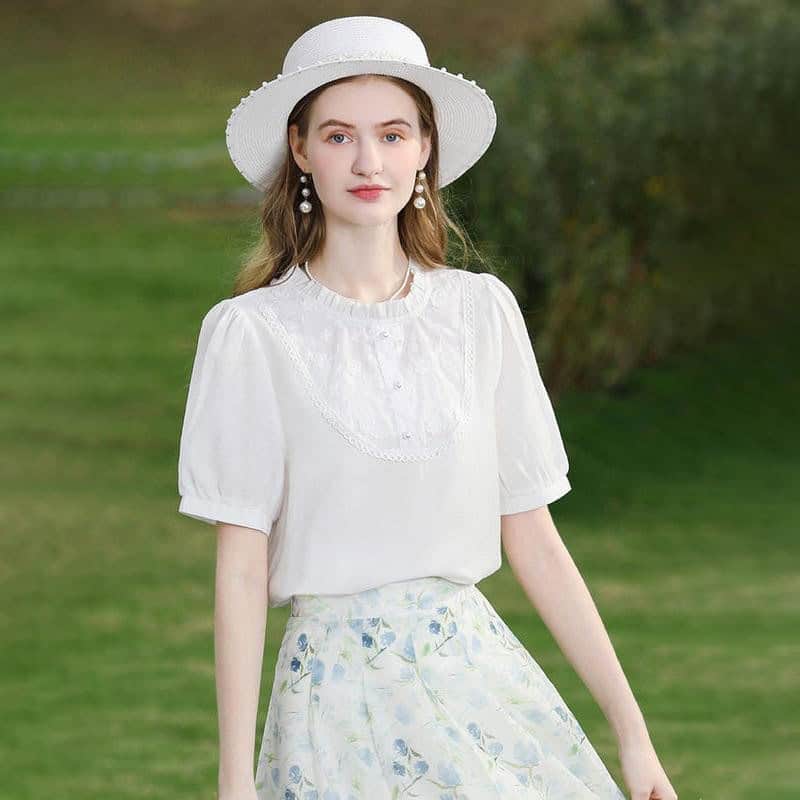 Young woman wearing stylish white hat and dress outdoors.