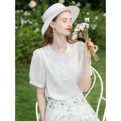 Beautiful young woman enjoying spring outdoors in stylish white blouse and floral skirt, holding a bouquet of flowers, showcasing elegant casual fashion by Monalisa Store.