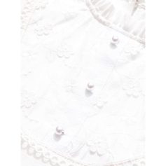 Close-up of a white blouse with delicate embroidery and pearl buttons, ideal for stylish and sophisticated fashion choices.