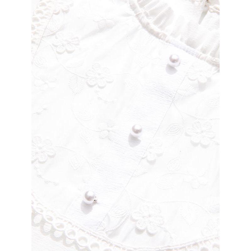 Close-up of a white blouse with delicate embroidery and pearl buttons, ideal for stylish and sophisticated fashion choices.