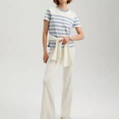 Elegant casual woman fashion with striped top and wide-leg pants, accessorized with a sweater tied around the waist, perfect for stylish everyday wear.