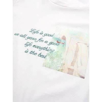 Light-colored T-shirt with inspirational quote “Life is good we all yearning for a good life everything is the best” embroidered in blue thread.