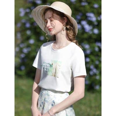 Stylish wide-brim straw hat, casual white graphic tee, and floral skirt perfect for summer outings and outdoor activities.