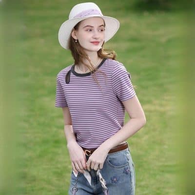 Young woman wearing a striped t-shirt, wide-brim hat, and denim jeans outdoors, showcasing casual fashion for women.