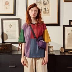 A young woman with red hair wearing multicolored casual clothing and glasses, showcasing stylish eyewear options at Monalisa Store. Perfect for trendy eyewear shopping and optical fashion needs.